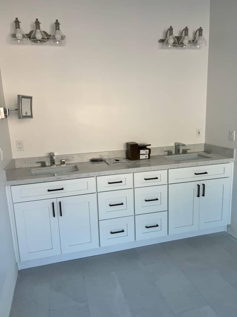 Modern bathroom vanities with white cabinetry and grey countertops, showcasing custom bathroom remodeling.